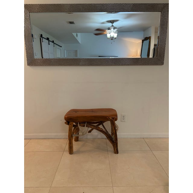A rustic accent table featuring a thick, polished live-edge wood top with a warm natural finish. Supported by an organic...