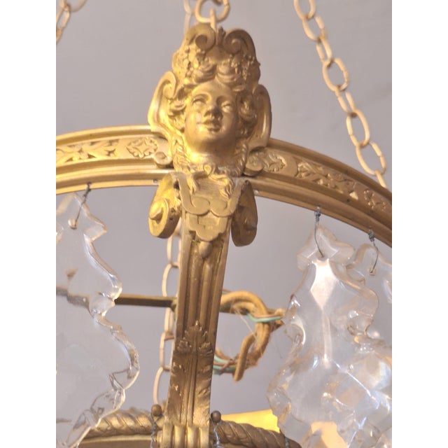 A striking antique French Empire–style chandelier featuring a finely cast gilt bronze frame adorned with elegant classical...