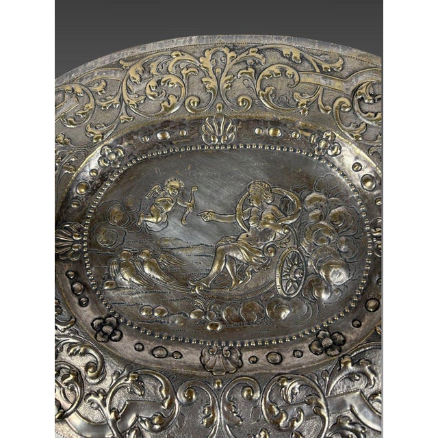 A 17th-century silvered bronze offering dish depicting Venus's chariot drawn by Cupid, with doves meeting Cupid. Finely...