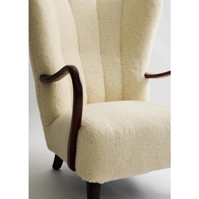 A Danish wingback lounge chair, circa 1960s, attributed to Alfred Christensen. Recently reupholstered in cream lambswool,...