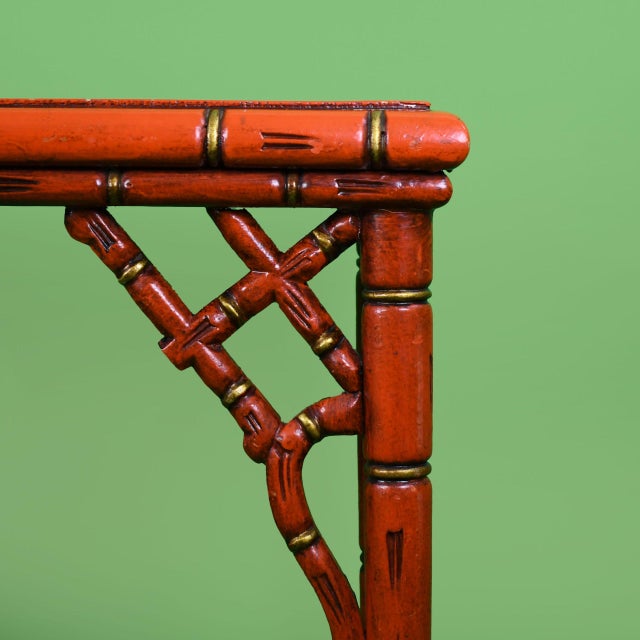 An Italian faux bamboo console in bold red and gold, with turned faux bamboo framing and a glamorous gilt finish. The slim...