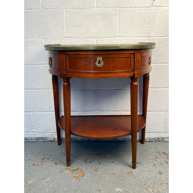 Elegant French demilune boutique table crafted in warm walnut, accented with refined brass trim and topped with marble....