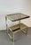 Elegant hollywood regency side table crafted in gold-plated metal, featuring a distinctive g-shaped structure that gives...