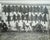 This evocative black-and-white photograph captures a moment from a bygone era, showcasing two men and their hunting dogs...