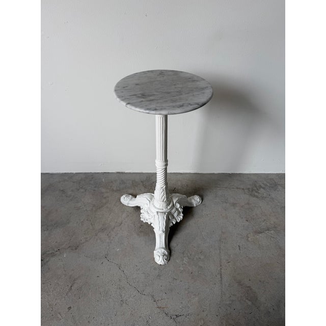 An elegant 19th-century French bistro table featuring a beautifully veined white marble top supported by an ornate cast-...