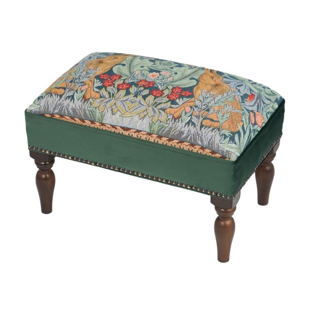 Meticulously handcrafted in the United Kingdom, this upholstered stool boasts classic studding and hand-polished solid...