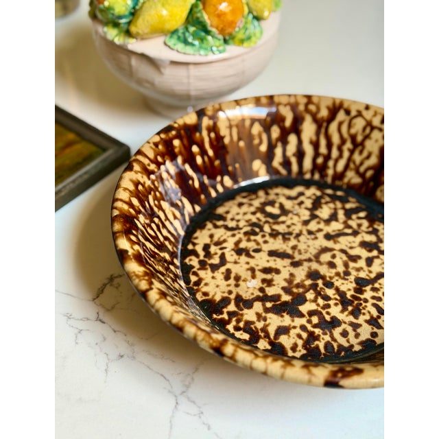 A classic antique bowl in the Rockingham Bennington style, featuring warm brown spongeware decoration with characteristic...