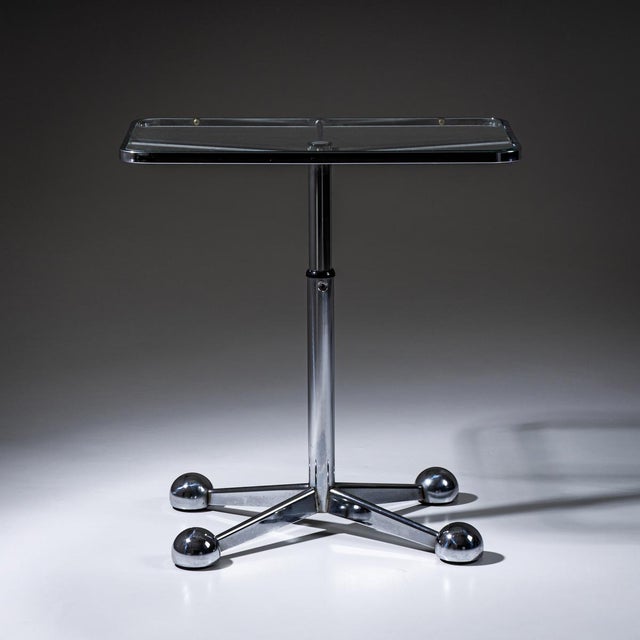 Glass table featuring a rectangular clear-glass top with rounded corners. The structure incorporates a cross-shaped...