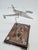 An original aviation-themed souvenir featuring a metal model airplane mounted on an elegant wooden base with an engraved...