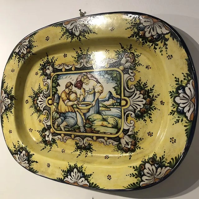 Hand painted ceramic wall plate featuring a man and woman by a stream in yellow and blue colors. Hand made items may vary...