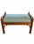 A distinctive upholstered bench featuring a warm, richly figured wood frame and blue-green upholstery patterned with small...