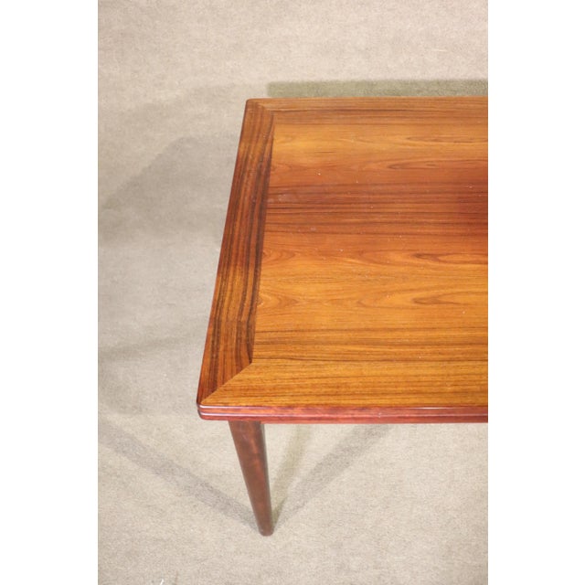 Danish made dining table in rich rosewood grain. Two leaves hide underneath the table top and are easily pulled out to...