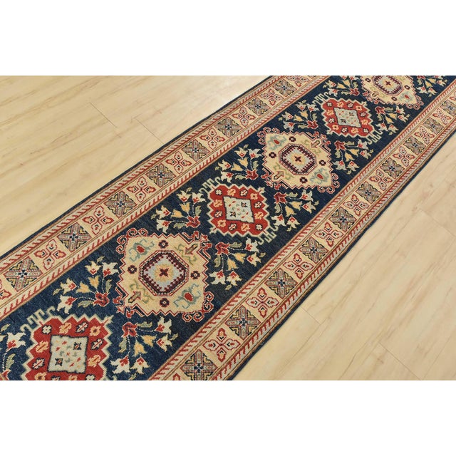 A traditional Caucasian Kazak runner hand-knotted with fine wool on a cotton foundation. This rug features a row of...