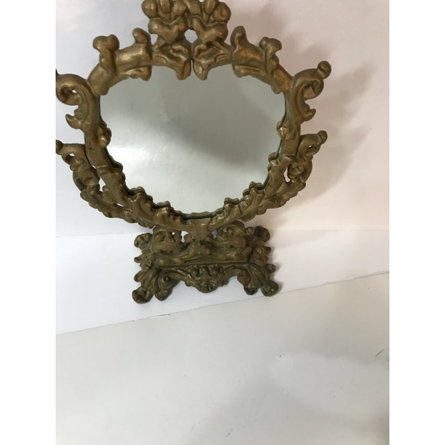 This darling petite tilting mirror, for table top, is gold painted cast iron. This is quite heavy being made of cast iron....