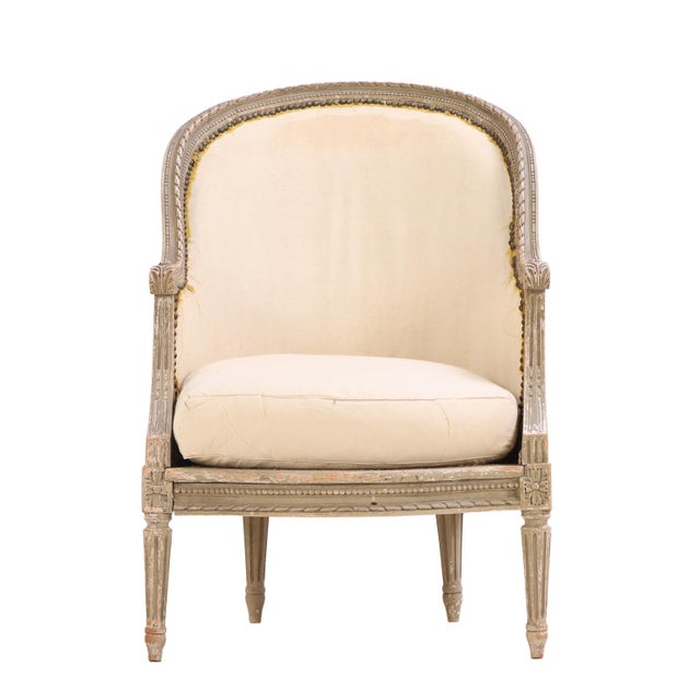 Elegant French bergère in the Louis XVI style, featuring an arched crest and caned back and sides. The padded back and...
