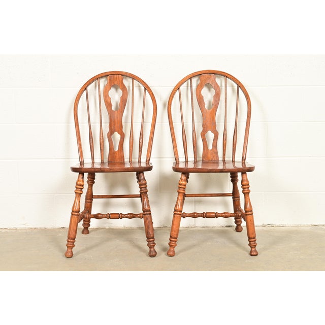 A gorgeous pair of American Colonial style solid oak spindle back Windsor side chairs or dining chairs In the manner of...