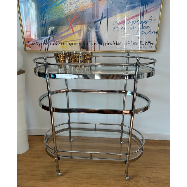 This stylish modern and sleek vintage bar cart features a heavy chrome construction with 3 thick clear glass oval shelves...
