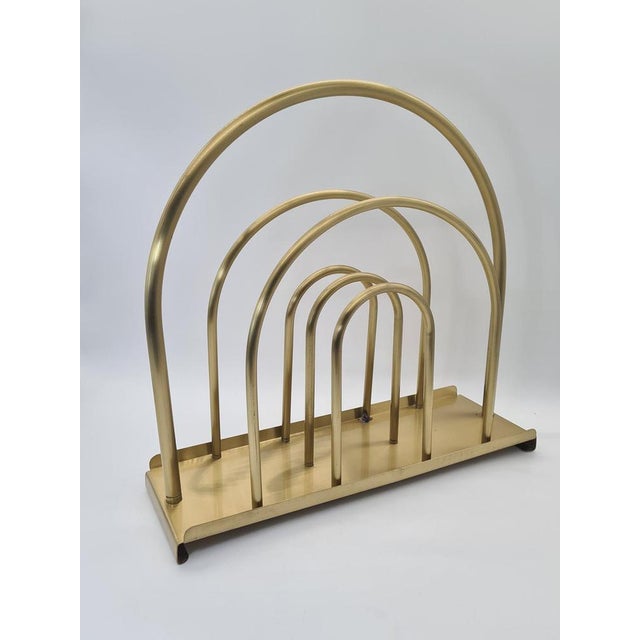 A stylish, vintage magazine rack made of metal with a brass-effect finish. The design, based on rhythmically repeating,...