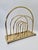 A stylish, vintage magazine rack made of metal with a brass-effect finish. The design, based on rhythmically repeating,...