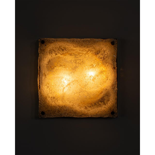 A sculptural Murano glass wall lamp featuring a bold three-dimensional wave relief in textured clear glass with shimmering...