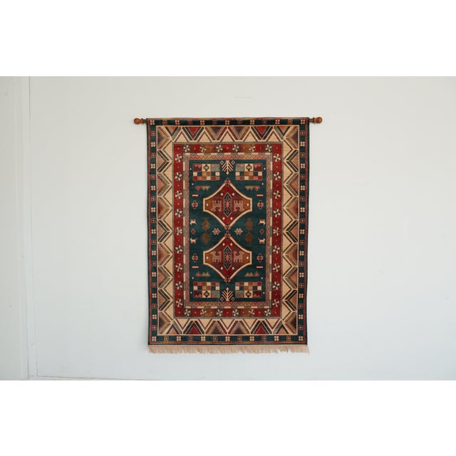 This vintage woven wall tapestry features a bold geometric motif in rich tones of teal, rust, and sand. Crafted from a...