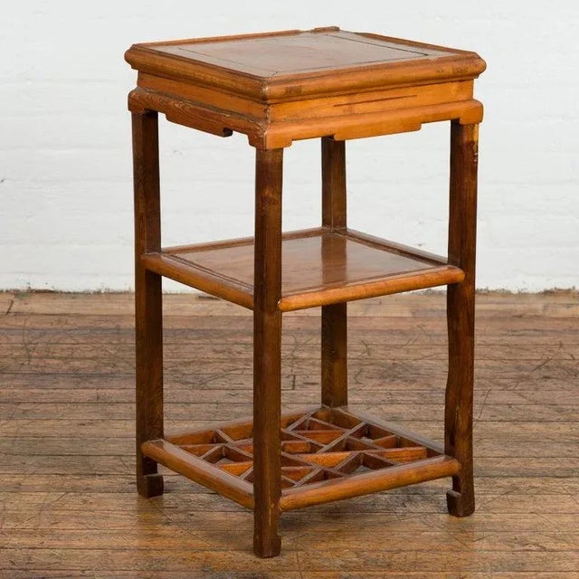 A Chinese late Qing Dynasty period lamp table from the early 20th century, with carved apron, shelves, cracked ice...