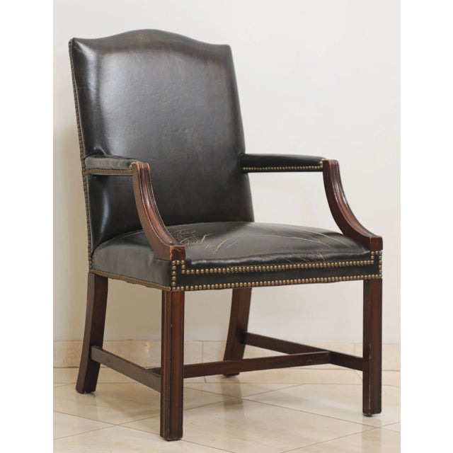 Manufactured by Kindel Grand Rapids distressed armchair with worn black tortoise leather upholstery and wooden frame....