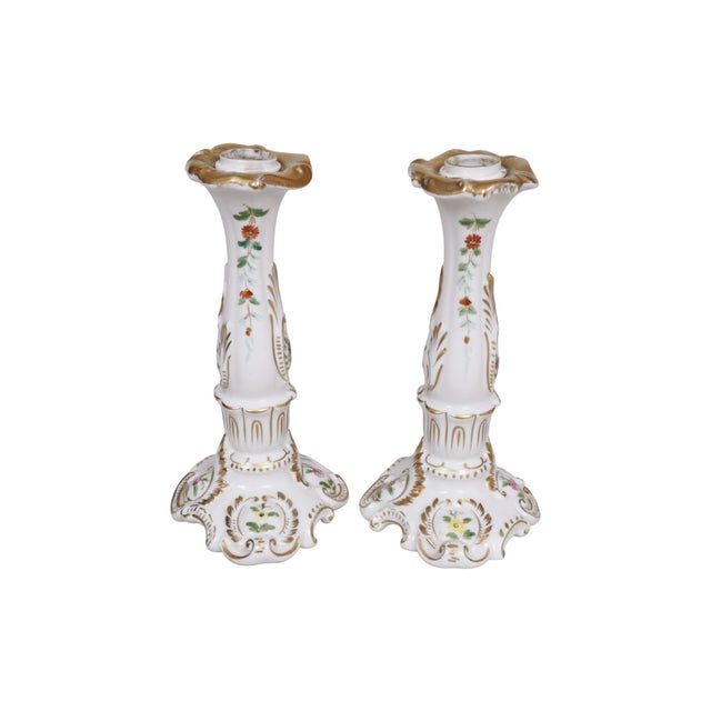 A pair of Meissen style German porcelain candlestick holders. Decorated with a floral motif and finished with gilt details...