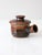 This small vintage studio pottery pot has a lid and side handle, finished in a rich, earthy glaze of brown and black...