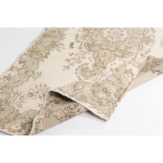 This is a vintage Turkish Oushak rug from the Mid 20th Century. The piece was hand-knotted.