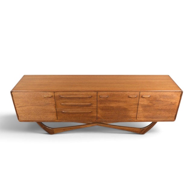 This large credenza was designed by Val Rossi and produced by Beithcraft in Scotland during the 1960s. The teak case rests...