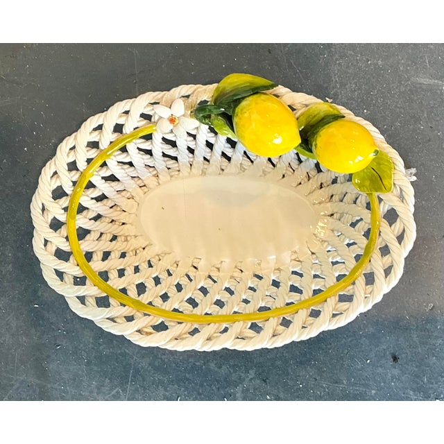 This charming Italian majolica basket bowl captures the sunny elegance of the Mediterranean with artisanal grace....