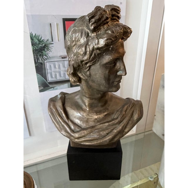 Neoclassic style bronze female bust. Mounted on a square black laminate-covered base.