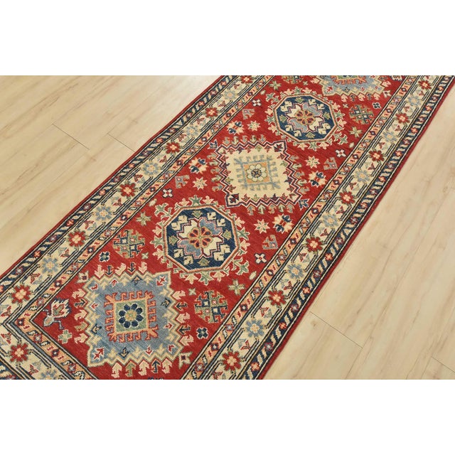 A tribal Caucasian Kazak runner hand-knotted with fine wool on a cotton foundation. This runner features a row of...