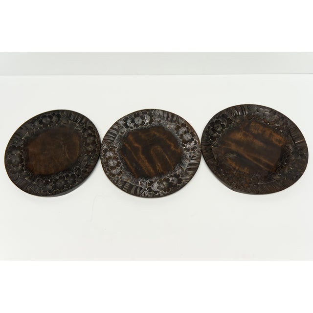 A set of three hand carved wooden decorative plates or trivets decorated with cherry blossoms on the edge. Finished with a...