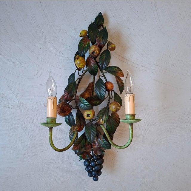 This wall lamp with 2 light points features metal fruit decoration in the shape of grapes, pears, lemons and a...