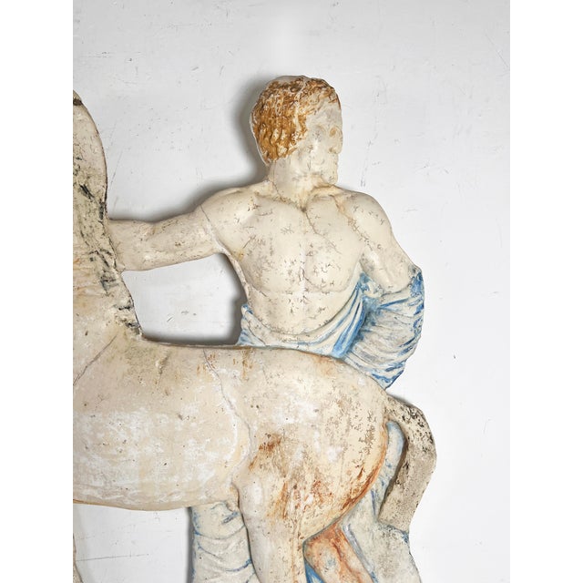 A late 19th century French neoclassical plaster relief sculpture of a toga clad figure with horse in faded polychrome.