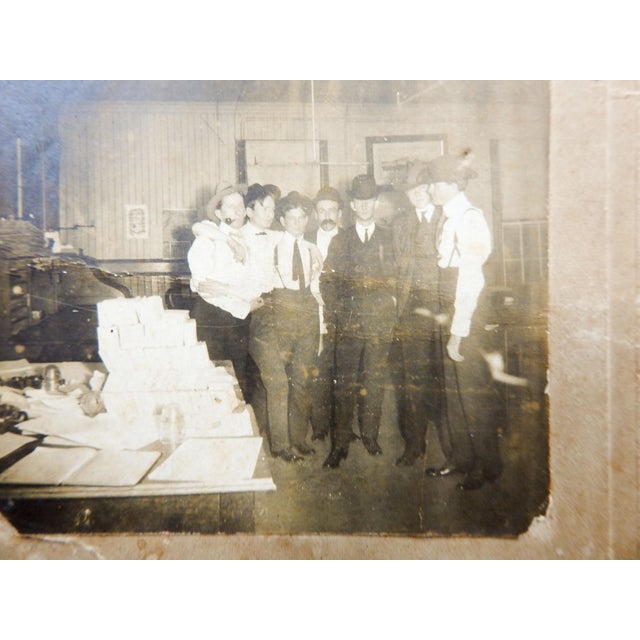 Vintage early 20th century silver gelatin photograph mounted on embossed cardboard backing. Group of men one with arms...
