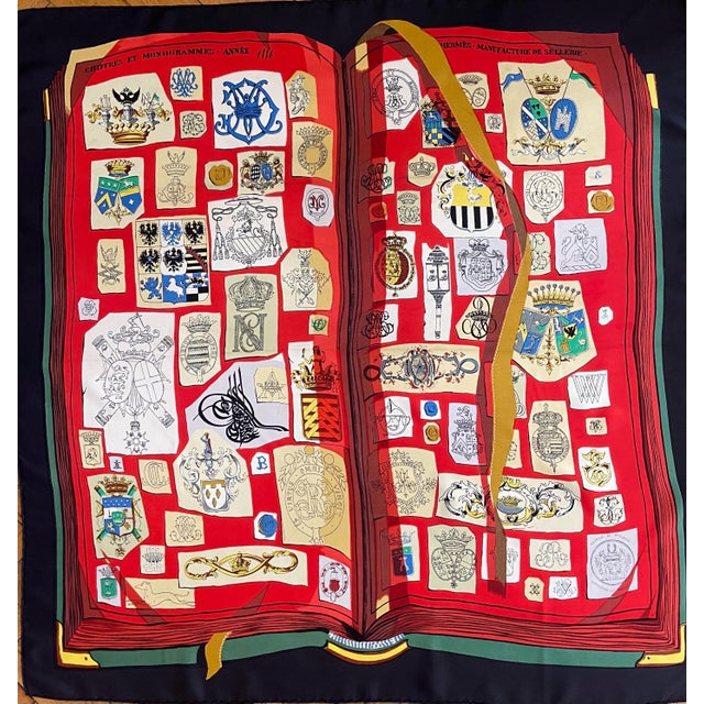 HERMES NUMBERS and MONOGRAMS red silk scarf, France This lovely scarf depicts an open book with a play of perspective that...