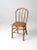 An antique farmhouse Windsor dining chair dating to the late 19th century. The painted wood chair features a gracefully...