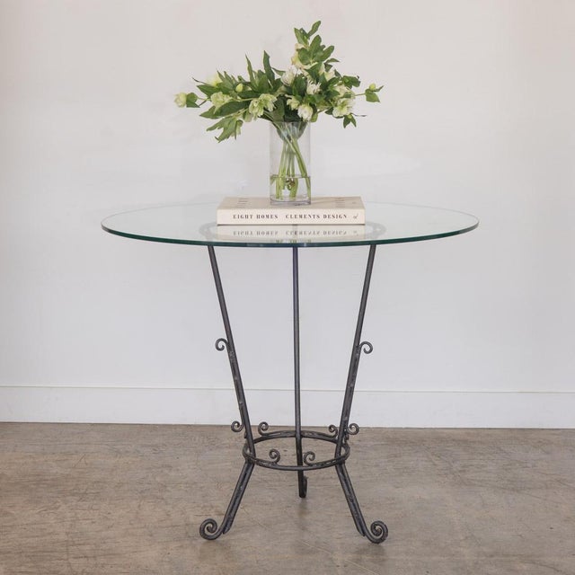 Beautiful wrought iron and glass center table from Spain, 1920s. Sculptural iron base with 3 curved legs and scroll...