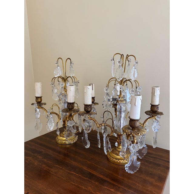 A beautiful pair of antique French girandole lamps, crafted in dore bronze and adorned with cascading crystal prisms,...