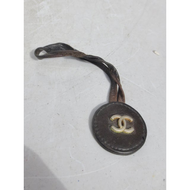 Bag Charm on black leather loop. Metal double CC on the face. The charm is 1.3" in diameter on a loop 3.5" long.