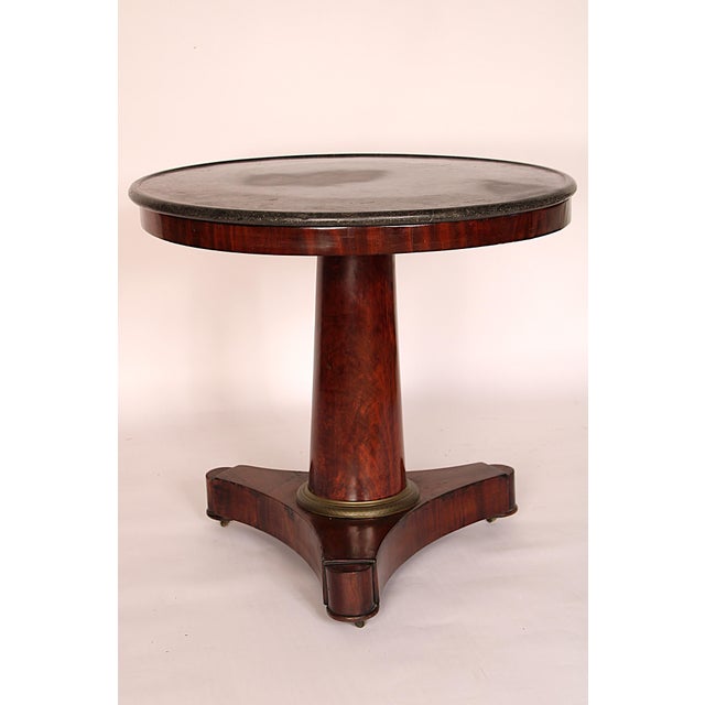 Period Empire mahogany center table with marble top, early 19th century. With a round marble top with molded edge, a flame...