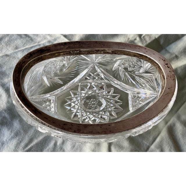 This is a sweet brilliant deeply cut glass bowl in an oval swooped boat shape. It has a nice heavy silver rim with an art...