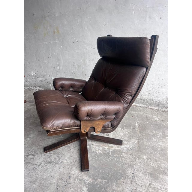 Comfortable vintage swivel lounge chair featuring a high backrest, padded headrest and generously upholstered armrests....