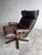 Comfortable vintage swivel lounge chair featuring a high backrest, padded headrest and generously upholstered armrests....