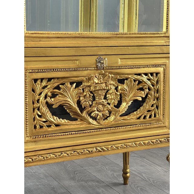 Elegant Louis XVI style carved and gilded wooden display cabinet. This piece is distinguished by the exquisite detail of...