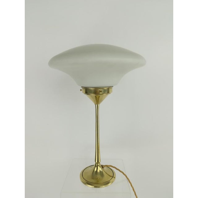 French table lamp made of solid brass polished, with mouth-blown glass shade. The lamp gives a cozy non-dazzling light....
