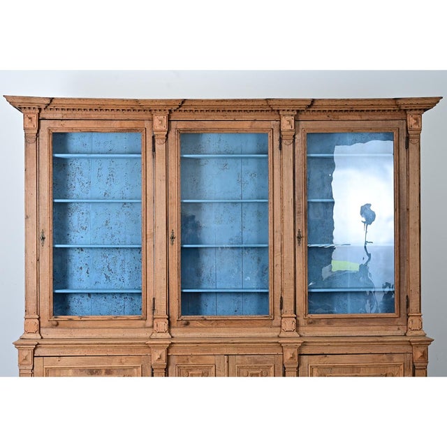 A large 19th-century French oak bibliotheque in a stripped finish. The cornice juts out sharply from the top and is...